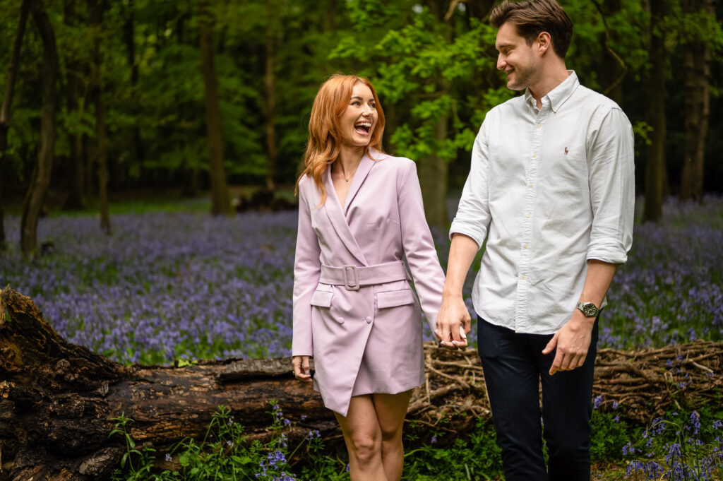 Engagement couple walking in woodlands with bluebells